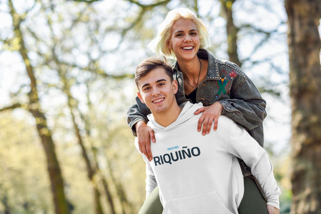 Un hombre cargando a una mujer sonriente sobre sus hombros en un parque soleado.