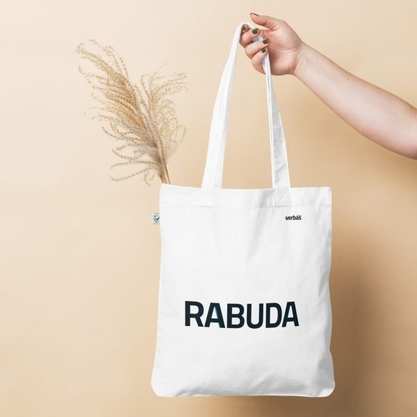 Una mano sostiene una bolsa de tela con la palabra RABUDA impresa, frente a un fondo beige.