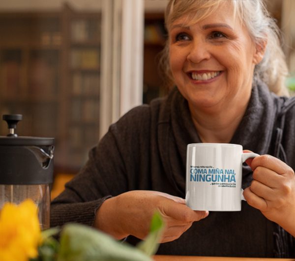 Una mujer sonriente sostiene una taza con texto