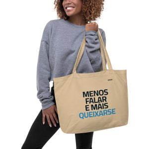 Una mujer sonriente lleva una bolsa de lona grande con un lema que dice Menos falar e mais queixarse